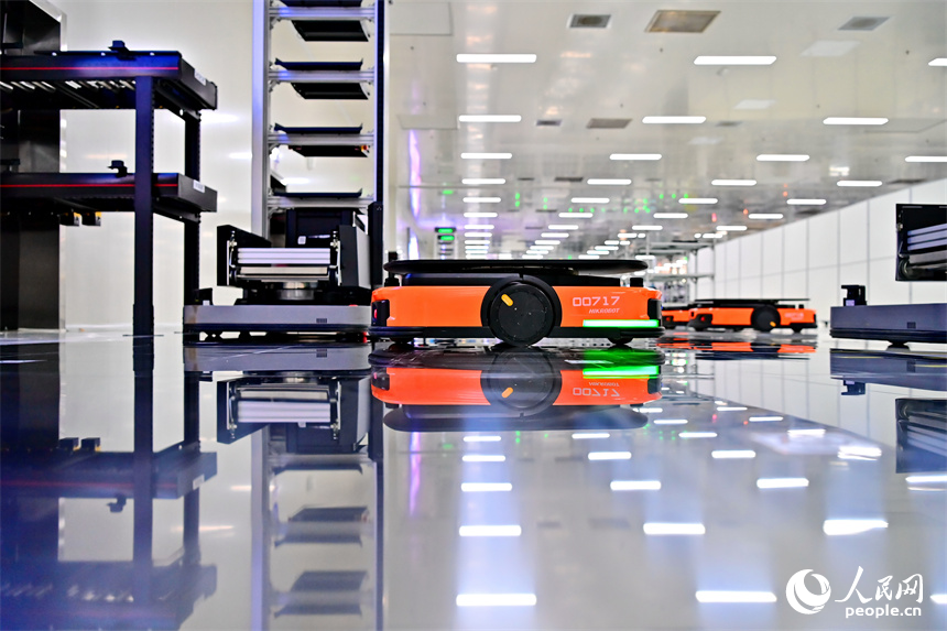 豐城市高新技術產業園區的一家汽車電子企業內,AGV運輸車來回運轉有序作業,工人在加工車載電子產品。人民網 朱海鵬攝