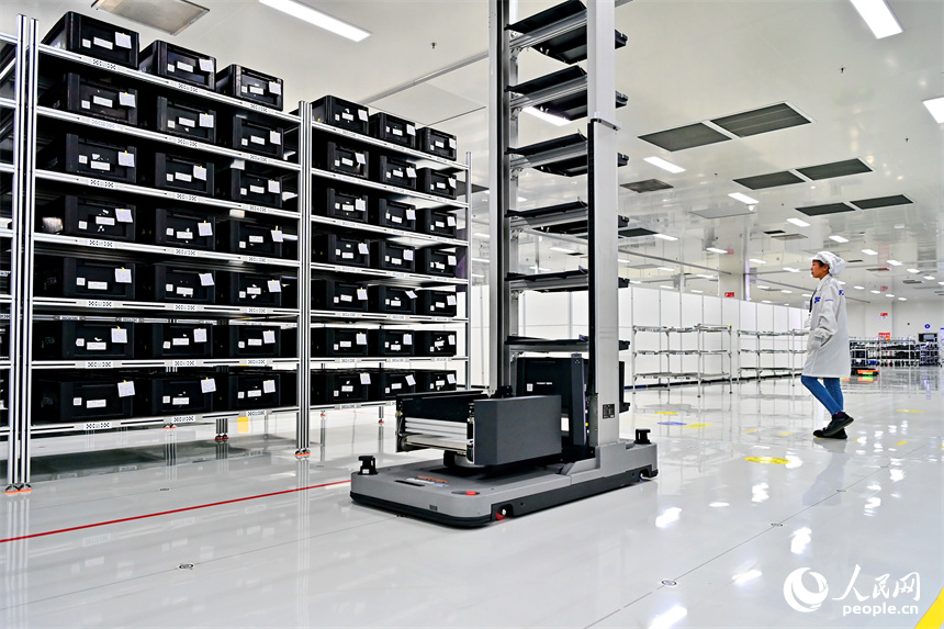 豐城市高新技術產業園區的一家汽車電子企業內，AGV運輸車來回運轉有序作業，工人在加工車載電子產品。人民網 朱海鵬攝