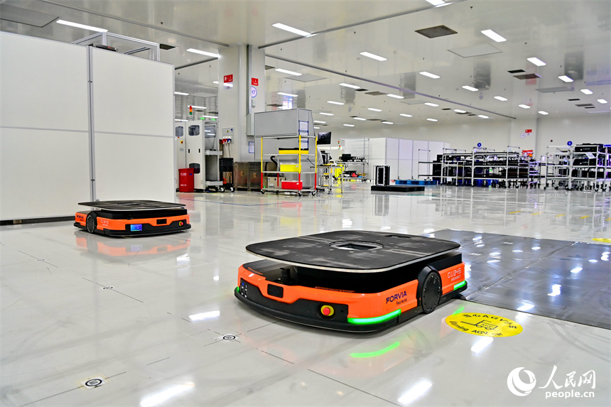 豐城市高新技術產業園區的一家汽車電子企業內，AGV運輸車來回運轉有序作業，工人在加工車載電子產品。人民網 朱海鵬攝