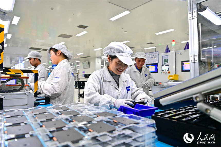 豐城市高新技術產業園區的一家汽車電子企業內，AGV運輸車來回運轉有序作業，工人在加工車載電子產品。人民網 朱海鵬攝