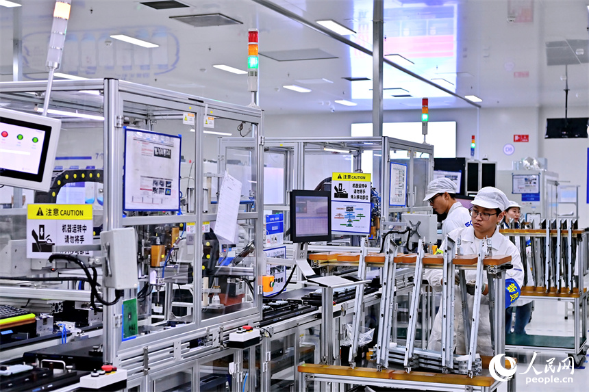 豐城市高新技術產業園區的一家汽車電子企業內，AGV運輸車來回運轉有序作業，工人在加工車載電子產品。人民網 朱海鵬攝