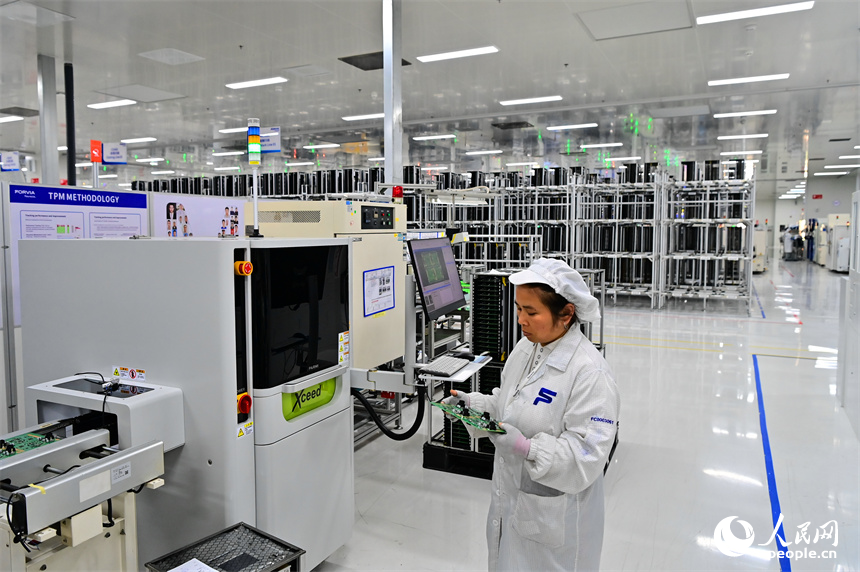 豐城市高新技術產業園區的一家汽車電子企業內，AGV運輸車來回運轉有序作業，工人在加工車載電子產品。人民網 朱海鵬攝