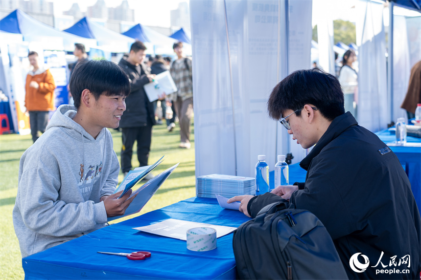 招聘會現場，用人單位正在與求職者交流。人民網 龍楚良攝