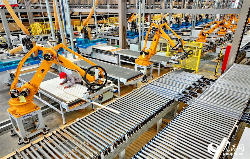 南康區的一家全屋定制家具生產企業智能制造車間內，工人在自動化生產線上調控智能機械臂加工板材。人民網 朱海鵬攝