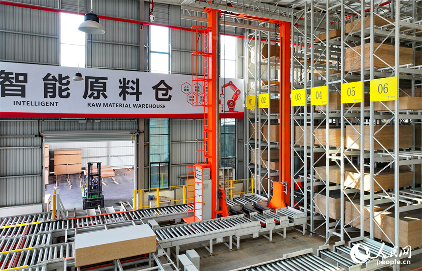南康區的一家全屋定制家具生產企業智能制造車間內，自動導引車和堆垛機在智能原料倉來回存取板材。人民網 朱海鵬攝
