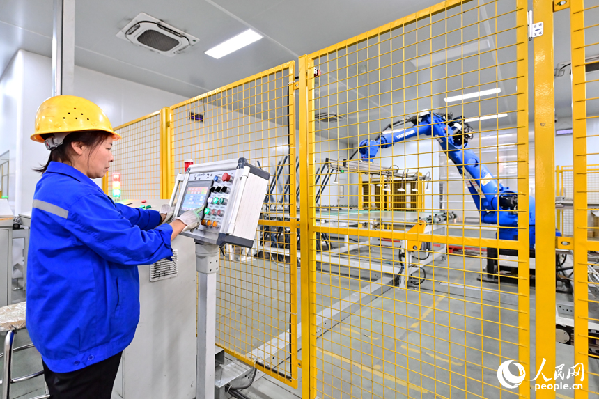 贛州市定南縣的一家新材料有限公司智能制造車間內，機器人手臂在來回循環作業，工人忙著加工光伏玻璃面板。人民網 朱海鵬攝