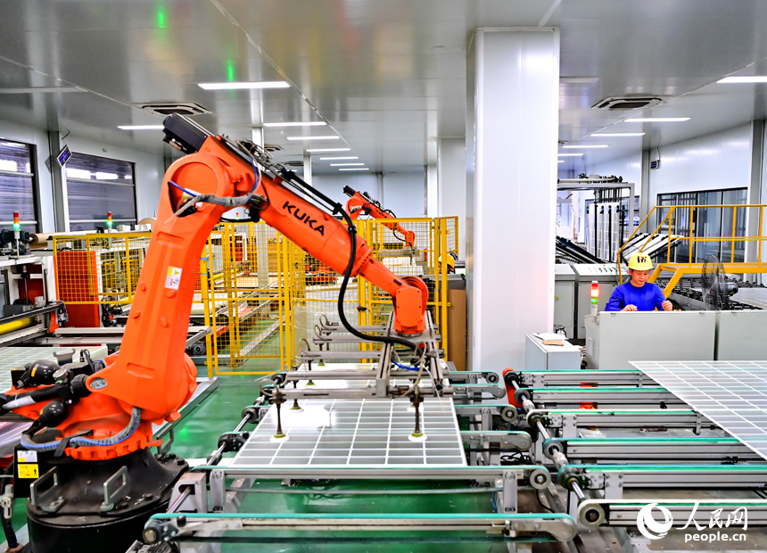 贛州市定南縣的一家新材料有限公司智能制造車間內，機器人手臂在來回循環作業，工人忙著加工光伏玻璃面板。人民網 朱海鵬攝
