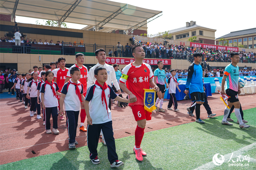 雙方足球聯隊參賽選手牽著球童，緩緩走進球場。人民網 涂詩軒攝