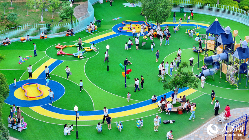 贛州市中心城區的一處公園里，家長帶著孩子在兒童游樂園內游玩，樂享親子時光。人民網 朱海鵬攝