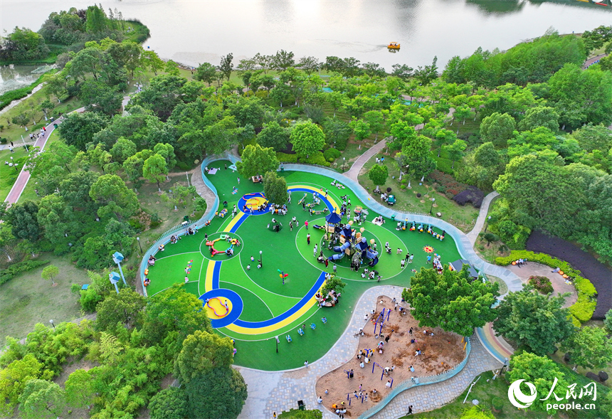 贛州市中心城區的一處公園里，家長帶著孩子在兒童游樂園內游玩，樂享親子時光。人民網 朱海鵬攝