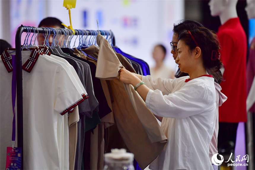 2025中國(南昌)國際服裝服飾博覽會在紅谷灘區舉行。圖為采購商正在挑選服飾產品。人民網記者 時雨攝