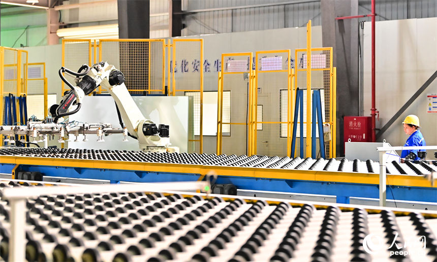贛州市定南縣的一家新材料企業生產車間的智能機械臂有序運轉，工人在自動化產線上加工光伏玻璃。人民網 朱海鵬攝
