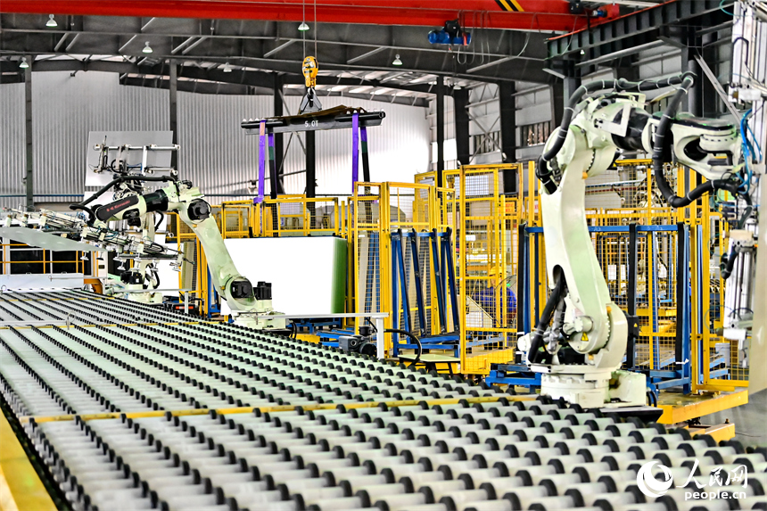 贛州市定南縣的一家新材料企業生產車間的智能機械臂有序運轉，工人在自動化產線上加工光伏玻璃。人民網 朱海鵬攝