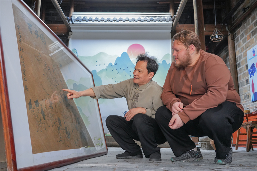 徐建元在向留學生白熙華介紹篾編作品《百子圖》。人民網 孔文進攝