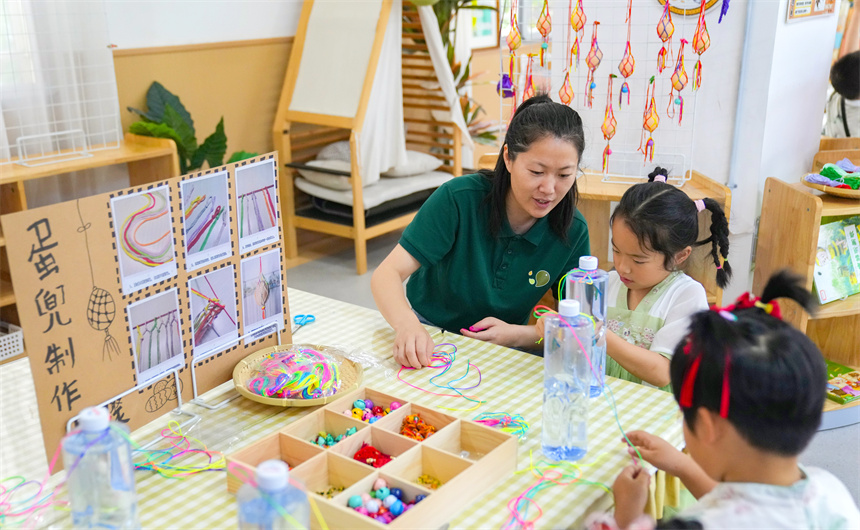 江西省撫州市臨川區保育院里，老師指導孩子們編蛋兜。郭昊攝