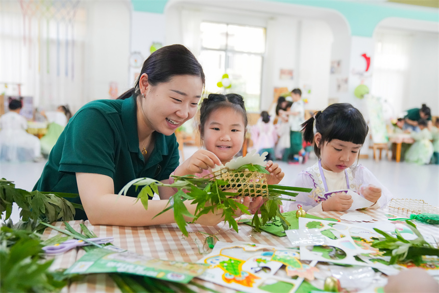 江西省撫州市臨川區保育院里，老師指導孩子們插艾籃。郭昊攝