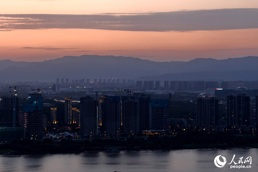 傍晚時分，染紅的天際映襯著梅嶺山脈，與城市初上的華燈相互輝映。人民網記者 時雨攝