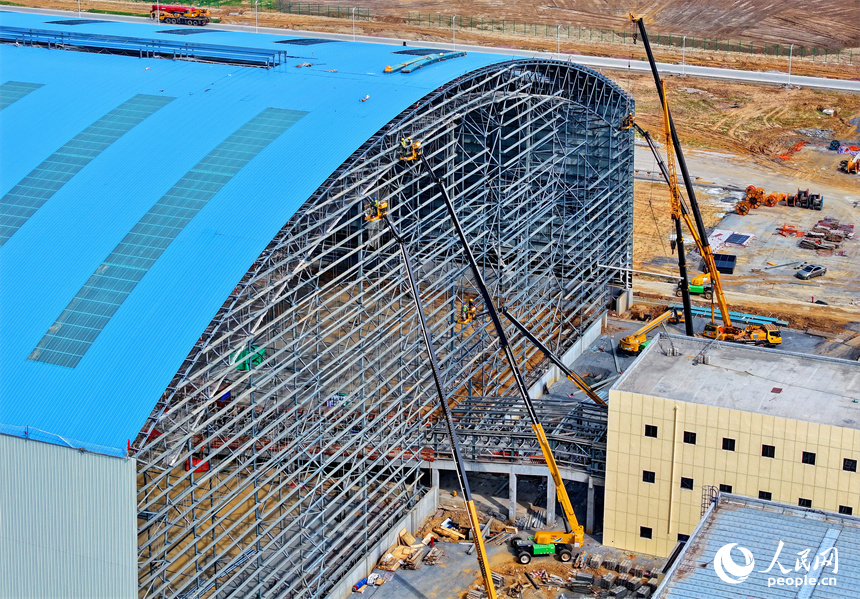 建設者們冒著高溫在高空進行貨棚擋板安裝作業。人民網 朱海鵬攝