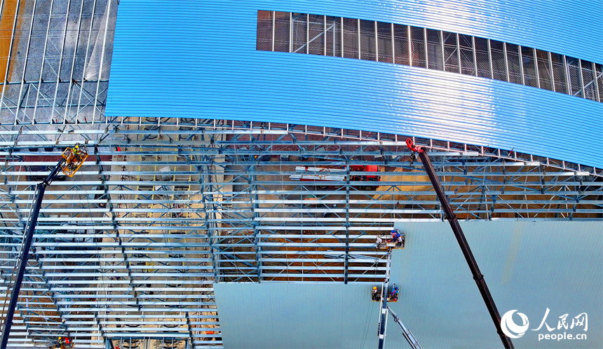 建設者們冒著高溫在高空進行貨棚擋板安裝作業。人民網 朱海鵬攝