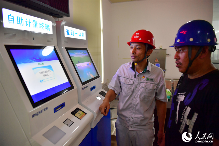 位于共青城市的中儲糧九江直屬庫的一站式服務中心內，工作人員正在協助糧農使用智慧終端查詢機。人民網記者 時雨攝