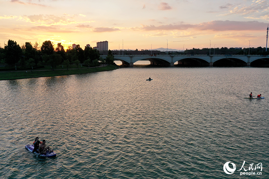 夕陽下，紅谷灘區九龍湖泛著金色波光，槳板愛好者們正在湖面揮槳劃行。人民網記者 時雨攝