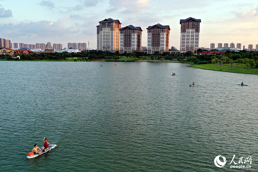 夕陽下，紅谷灘區九龍湖泛著金色波光，槳板愛好者們正在湖面揮槳劃行。人民網記者 時雨攝