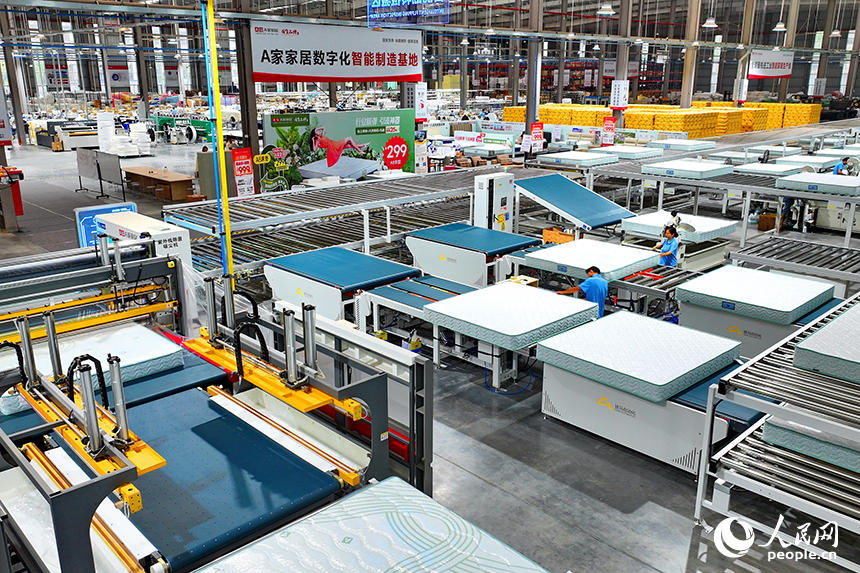 贛州市南康區的A家家居數字化智能制造基地，機械臂、傳輸機循環作業，工人在智能床墊生產線上趕制訂單產品。人民網 朱海鵬攝