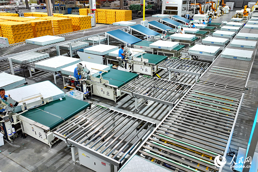 贛州市南康區的A家家居數字化智能制造基地，機械臂、傳輸機循環作業，工人在智能床墊生產線上趕制訂單產品。人民網 朱海鵬攝