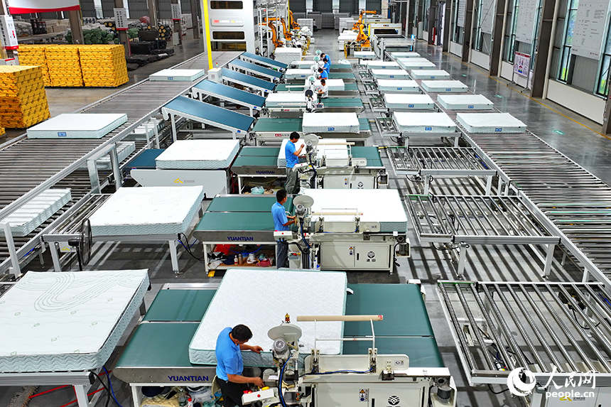 贛州市南康區的A家家居數字化智能制造基地，機械臂、傳輸機循環作業，工人在智能床墊生產線上趕制訂單產品。人民網 朱海鵬攝