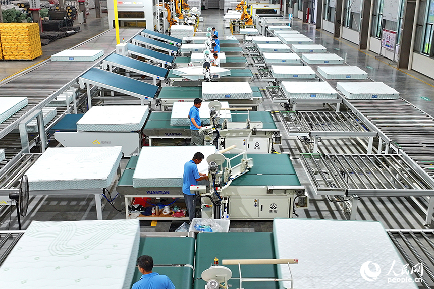 贛州市南康區的A家家居數字化智能制造基地，機械臂、傳輸機循環作業，工人在智能床墊生產線上趕制訂單產品。人民網 朱海鵬攝