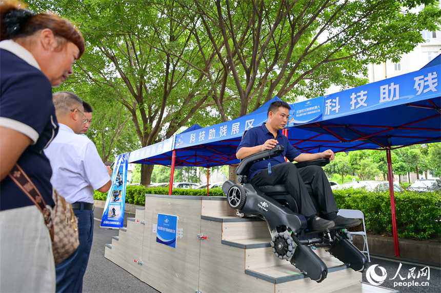 參觀者在科技助殘展區咨詢試用無障礙爬樓機器人產品。人民網 朱海鵬攝
