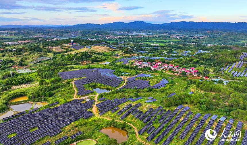 撫州市南豐縣萊溪鄉西山村“農光互補”光伏發電站，荒山坡上安裝的光伏板熠熠生輝，與綠樹青山相映相襯。人民網 朱海鵬攝