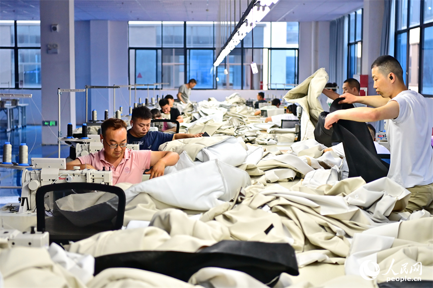贛州市南康區的一家“工業上樓”項目家具生產企業內，工人在加工軟體家具。人民網 朱海鵬攝