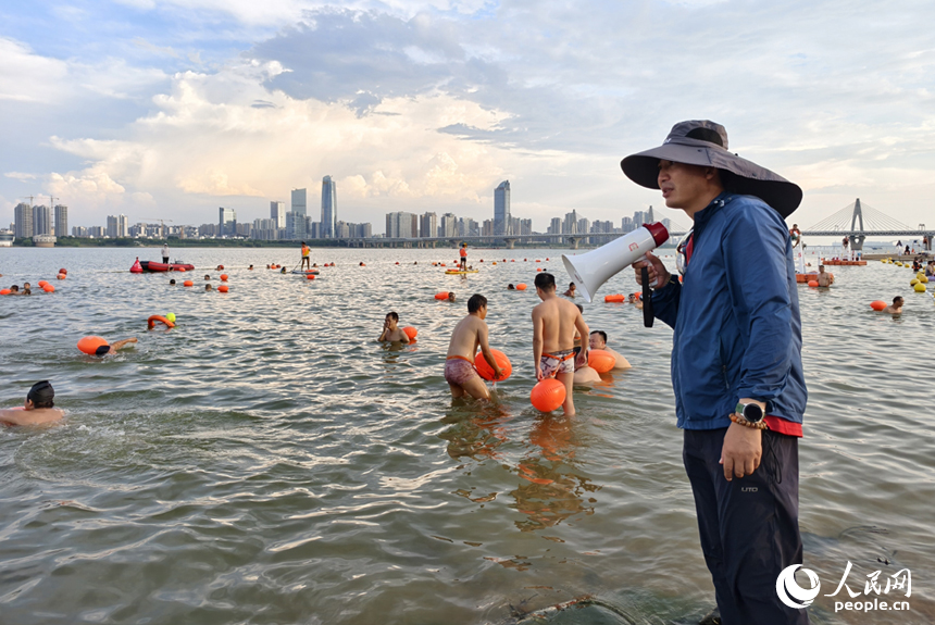 在岸邊的安全員通過高音喇叭提醒水中的市民注意安全。人民網記者 時雨攝