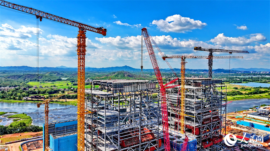 信豐電廠二期項目建設現場塔吊林立，施工作業有序，工人在吊裝鍋爐鋼結構設備。人民網 朱海鵬攝