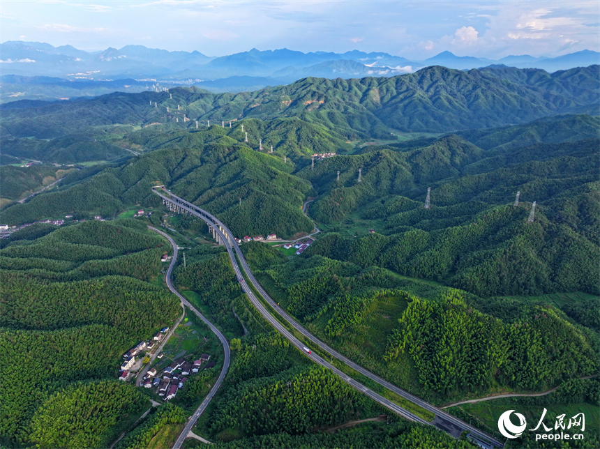 撫州市資溪縣嵩市鎮，撫（州）至吉（安）高速公路如同銀龍蜿蜒穿梭于蒼翠的崇山峻嶺間，與田園、村落相映成景。人民網 朱海鵬攝