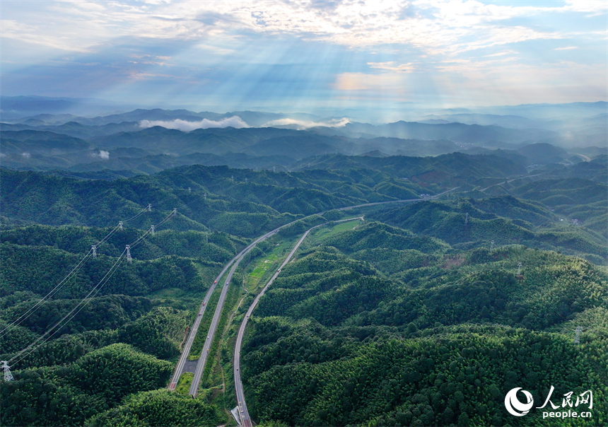 撫州市資溪縣嵩市鎮，撫（州）至吉（安）高速公路如同銀龍蜿蜒穿梭于蒼翠的崇山峻嶺間，與田園、村落相映成景。人民網 朱海鵬攝