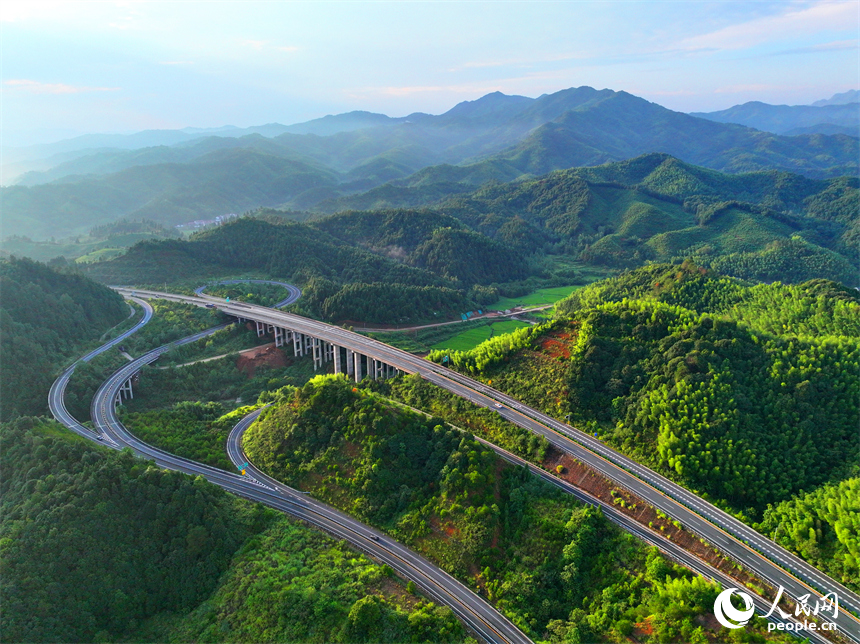 撫州市資溪縣嵩市鎮，撫（州）至吉（安）高速公路如同銀龍蜿蜒穿梭于蒼翠的崇山峻嶺間，與田園、村落相映成景。人民網 朱海鵬攝
