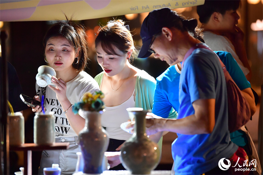 游客在春秋大集的攤位上挑選心儀的瓷器。人民網記者 時雨攝