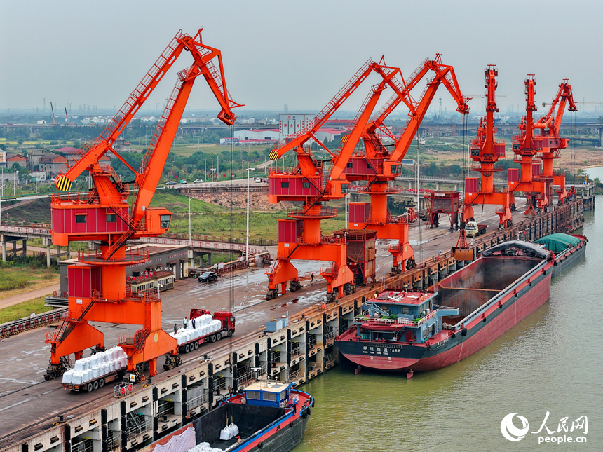 在姚灣綜合碼頭，運輸貨物的車輛往來穿梭，起重機裝卸作業有序進行。人民網 朱海鵬攝