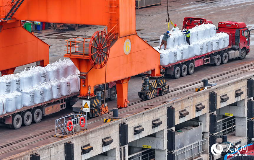 在姚灣綜合碼頭，運輸貨物的車輛往來穿梭，起重機裝卸作業有序進行。人民網 朱海鵬攝