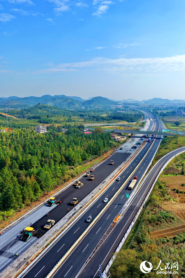 滬昆高速昌傅至金魚石（贛湘界）段改擴建項目施工現場機械轟鳴，工人在攤鋪路面瀝青。人民網記者 朱海鵬攝