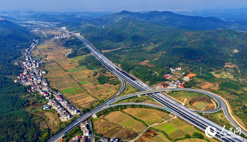 滬昆高速昌傅至金魚石（贛湘界）段改擴建項目施工現場機械轟鳴，工人在攤鋪路面瀝青。人民網記者 朱海鵬攝