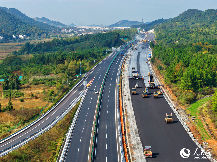 滬昆高速昌傅至金魚石（贛湘界）段改擴建項目施工現場機械轟鳴，工人在攤鋪路面瀝青。人民網記者 朱海鵬攝