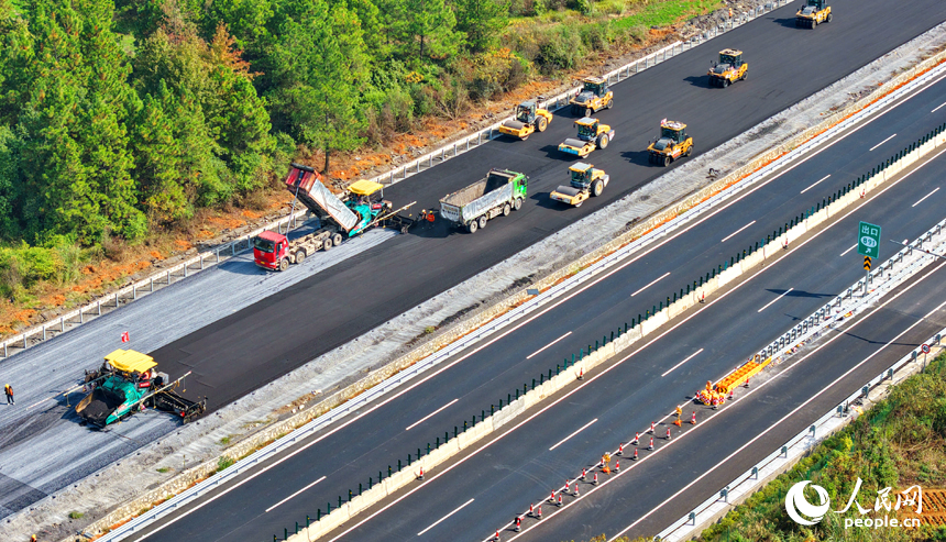 滬昆高速昌傅至金魚石（贛湘界）段改擴建項目施工現場機械轟鳴，工人在攤鋪路面瀝青。人民網記者 朱海鵬攝
