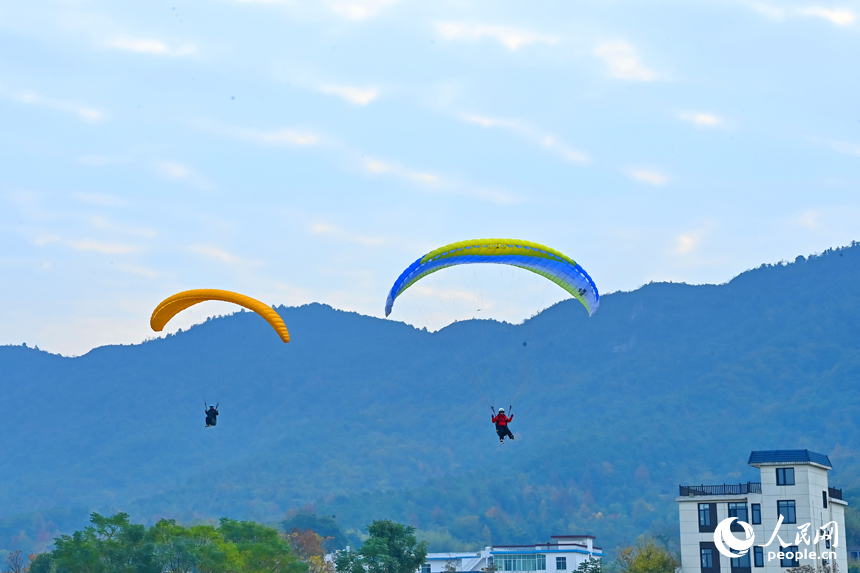 南康區龍回鎮布谷寨航空飛行營地，動力傘編隊、滑翔傘表演和比賽吸引眾多游客前來觀看。人民網記者 朱海鵬攝